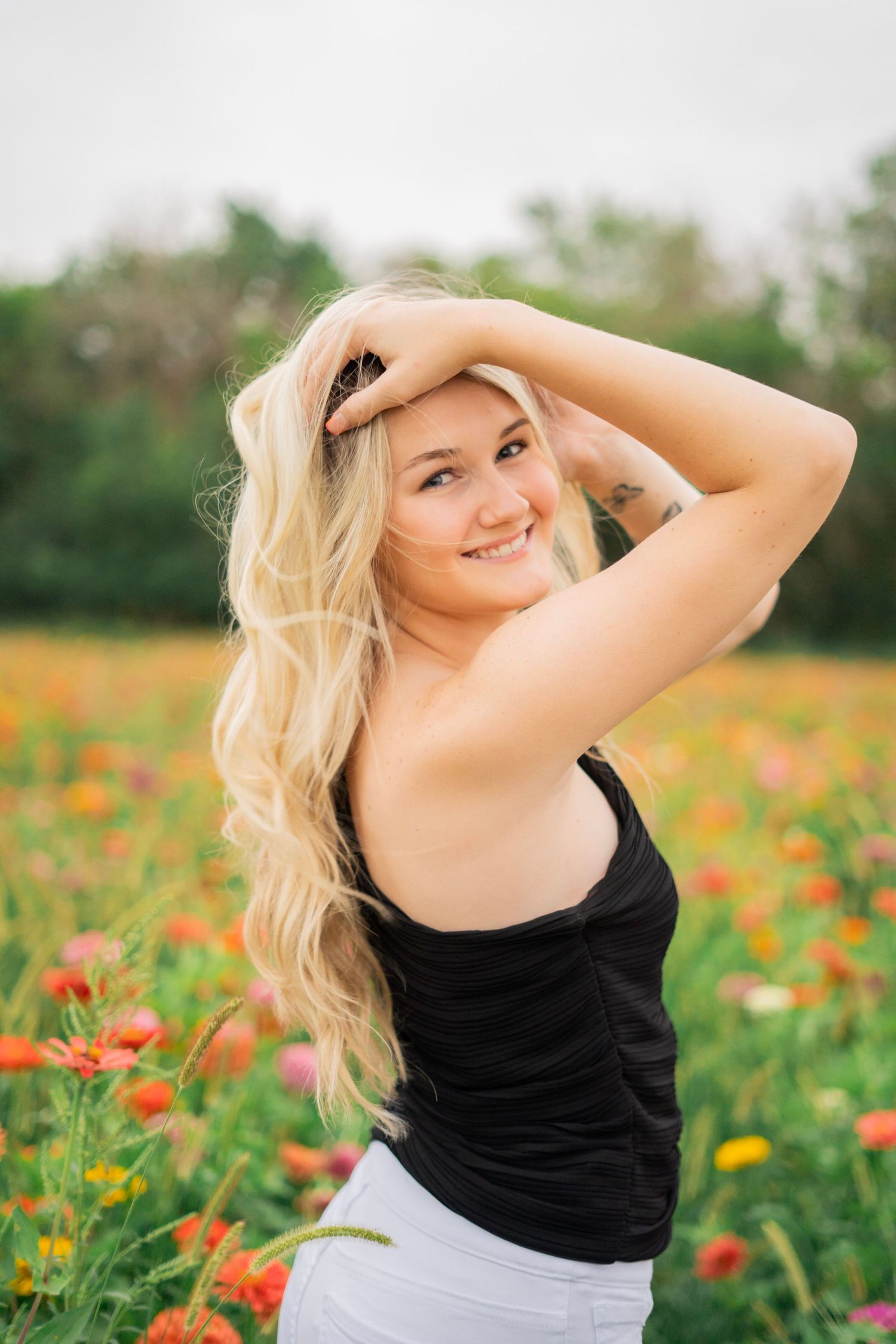 Blonde woman with long hair posing in a vibrant field of colorful wildflowers.