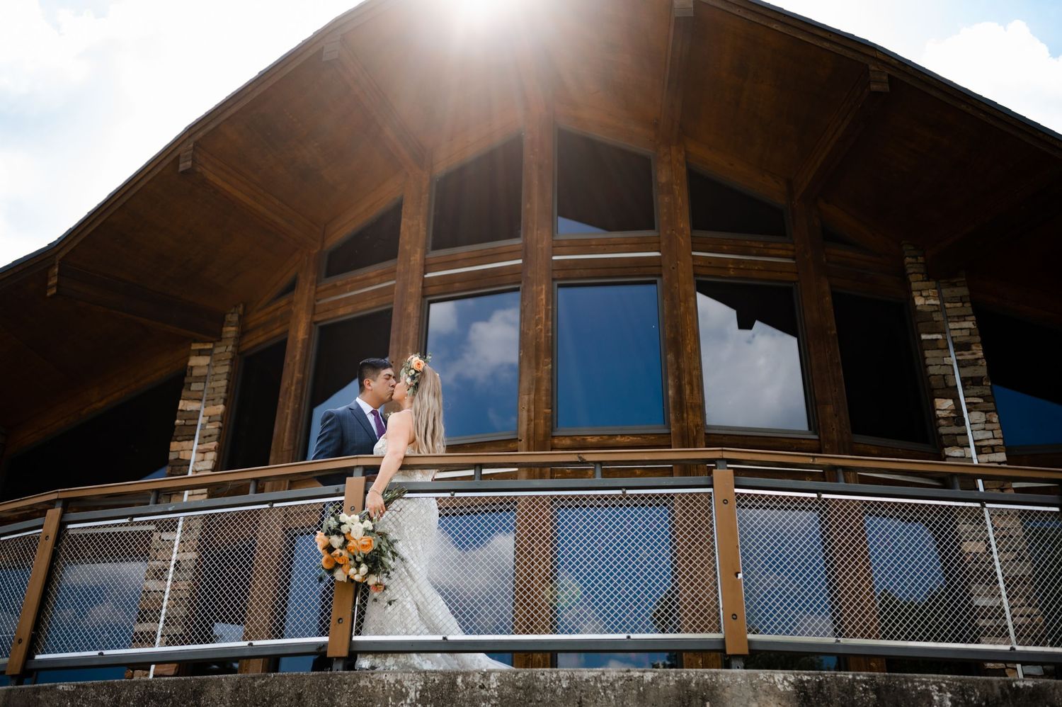 Modern rustic venue with large windows and balcony showcasing mountain wedding setting.