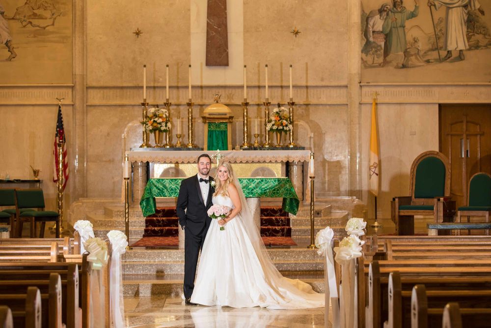 Wedding photo in traditional church sanctuary with ornate altar and candlesticks.