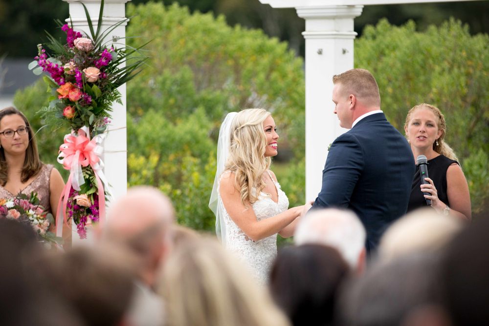 Outdoor wedding ceremony featuring pink and white floral arrangements on decorative pillars.