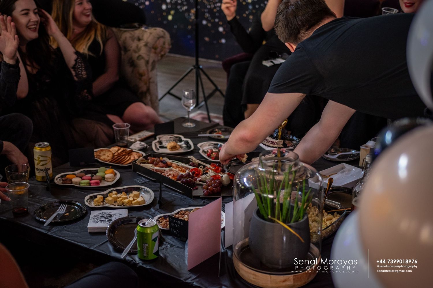 Dark atmospheric dining scene with people enjoying food and drinks at a table.