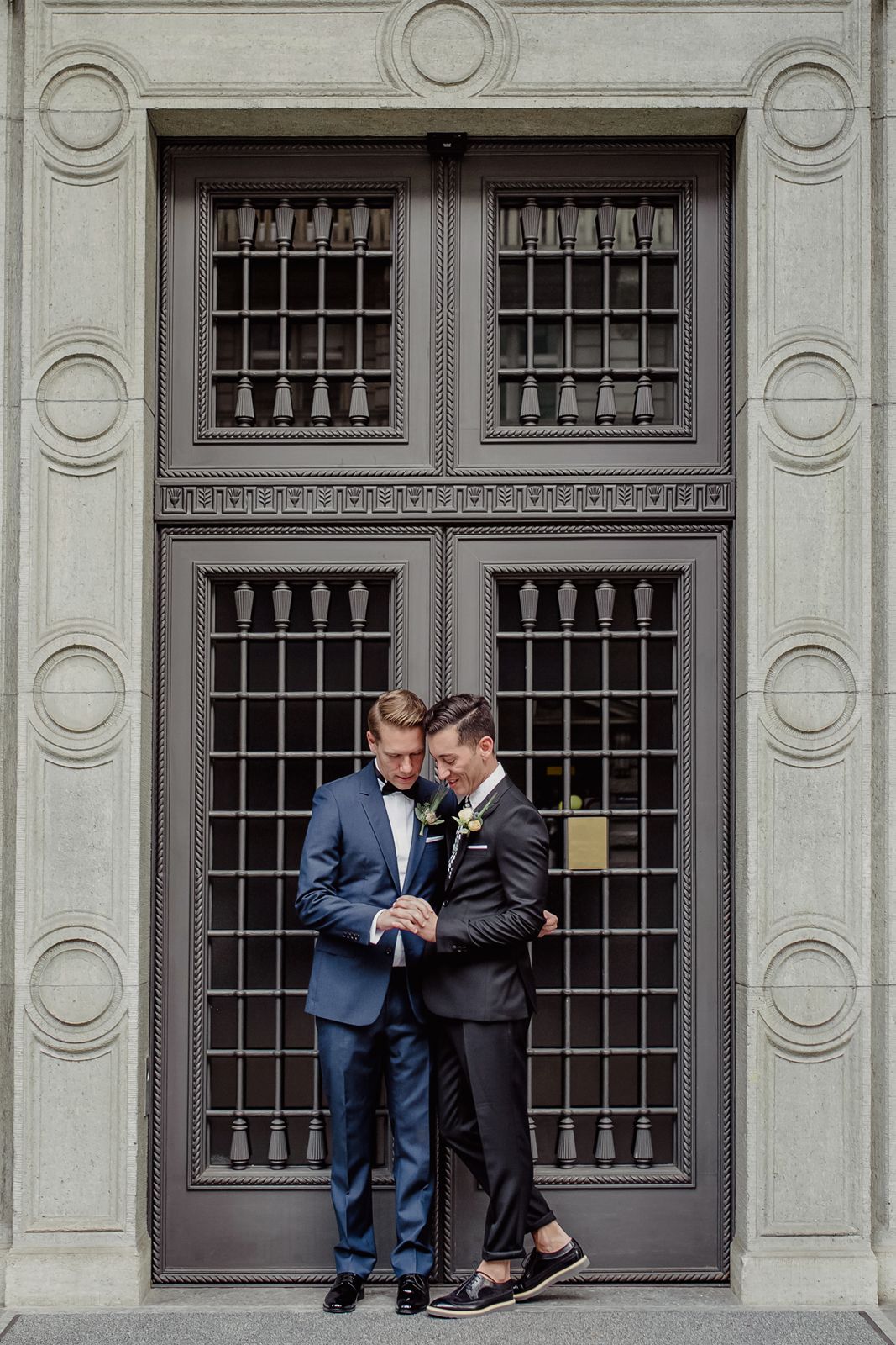 Full-length portrait of a couple standing in front of a tall, historic double door at a wedding venue in Zurich.