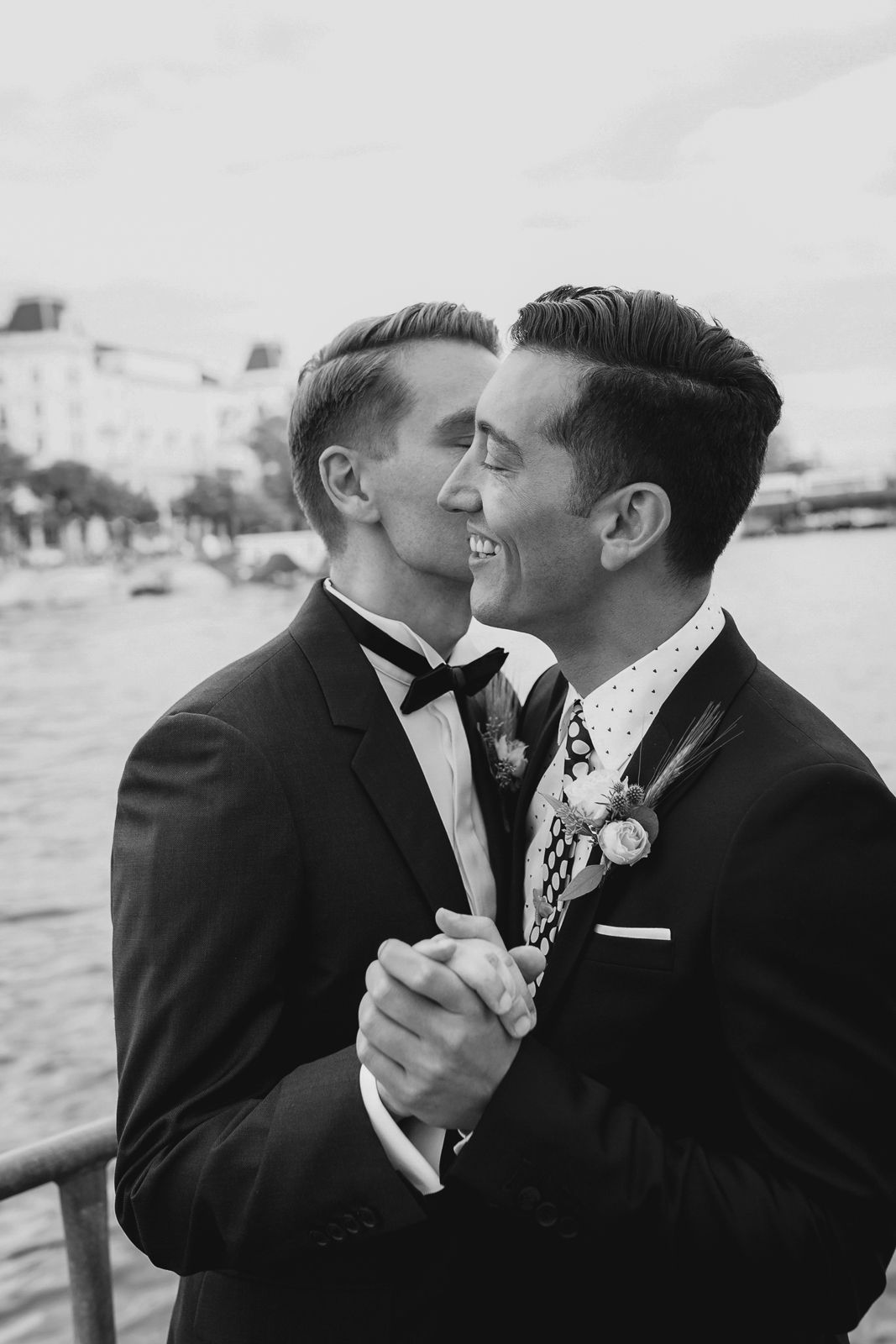 Close-up black and white wedding portrait of a groom smiling and leaning toward his partner.