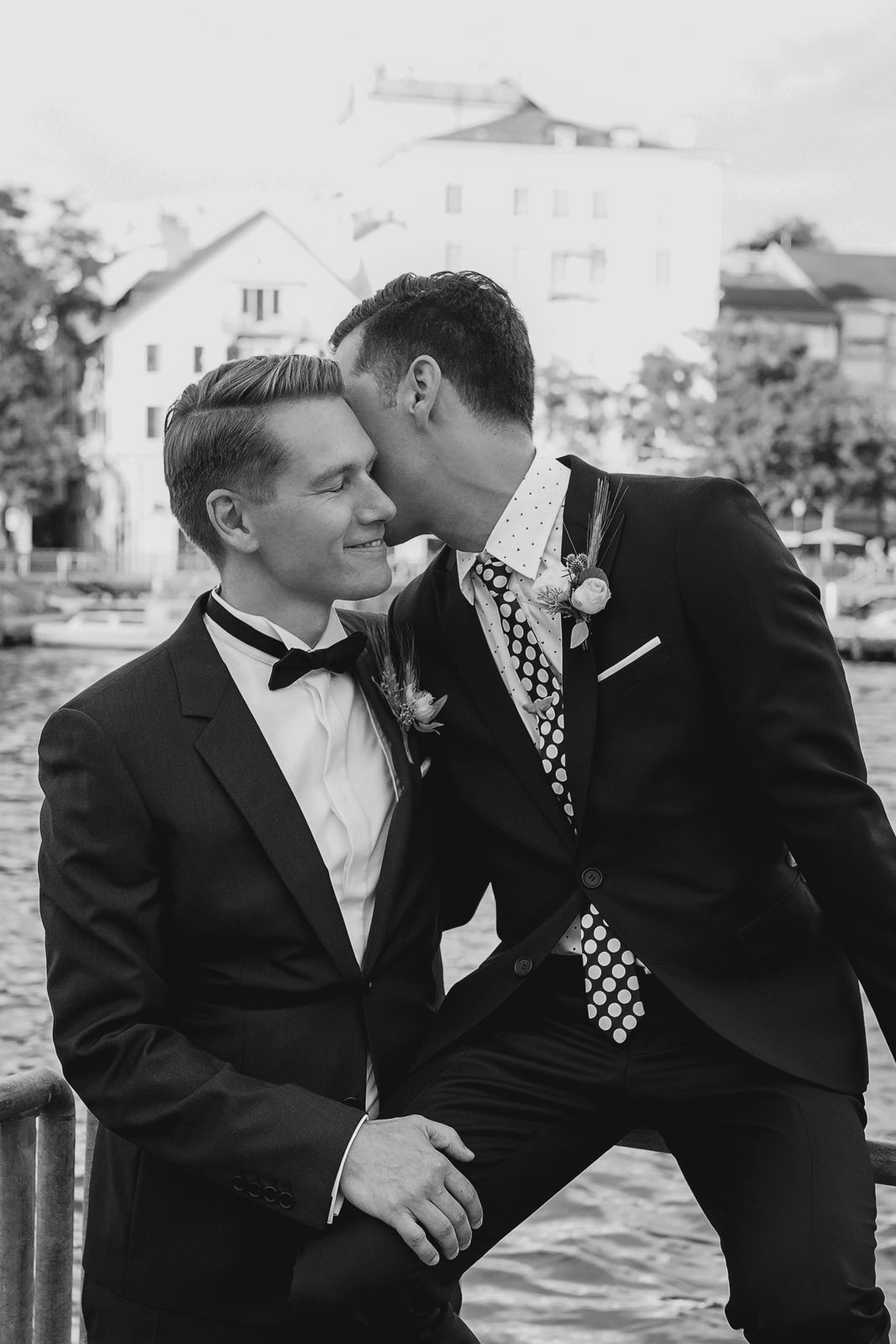 Black and white portrait of a groom laughing and leaning into his partner during a wedding shoot in Zurich.