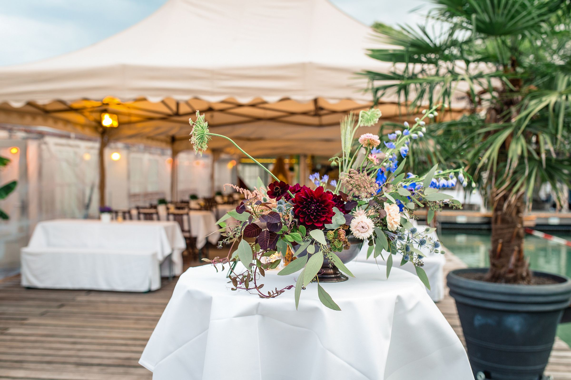 Outdoor wedding reception scene featuring lounge seating and floral decor under a white canopy tent.