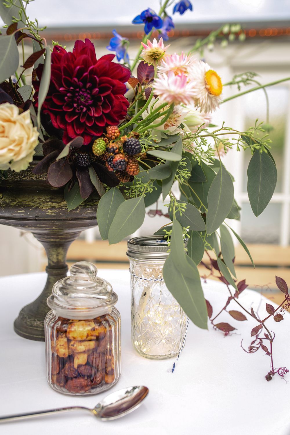 Vertical detail shot of an elegant wedding floral arrangement featuring deep red roses and greenery.