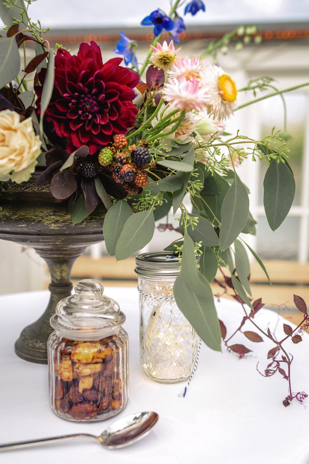 Vertical detail shot of an elegant wedding floral arrangement featuring deep red roses and greenery.