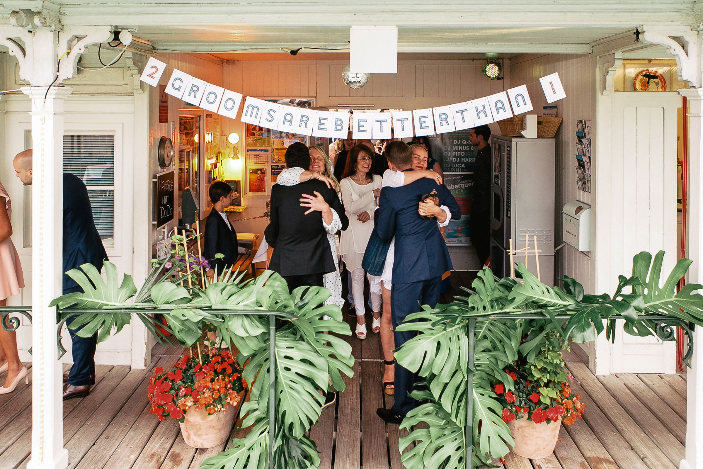 Wedding guests gathered at the entrance of a decorated venue with a festive "Better Together" banner.