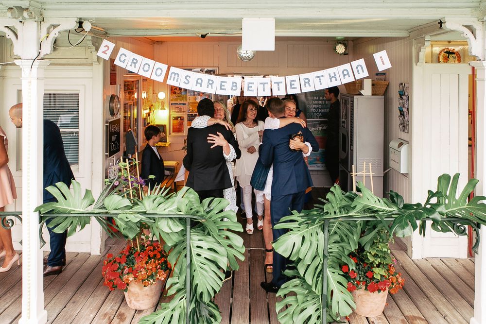 Wedding guests gathered at the entrance of a decorated venue with a festive "Better Together" banner.