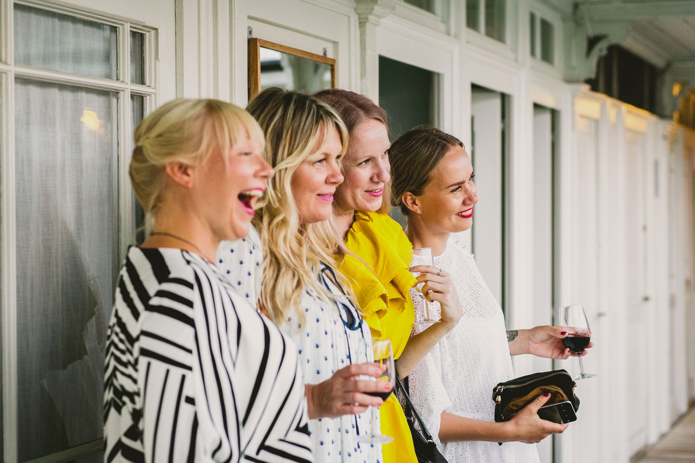 A group of wedding guests laughing and talking during a festive outdoor cocktail hour.