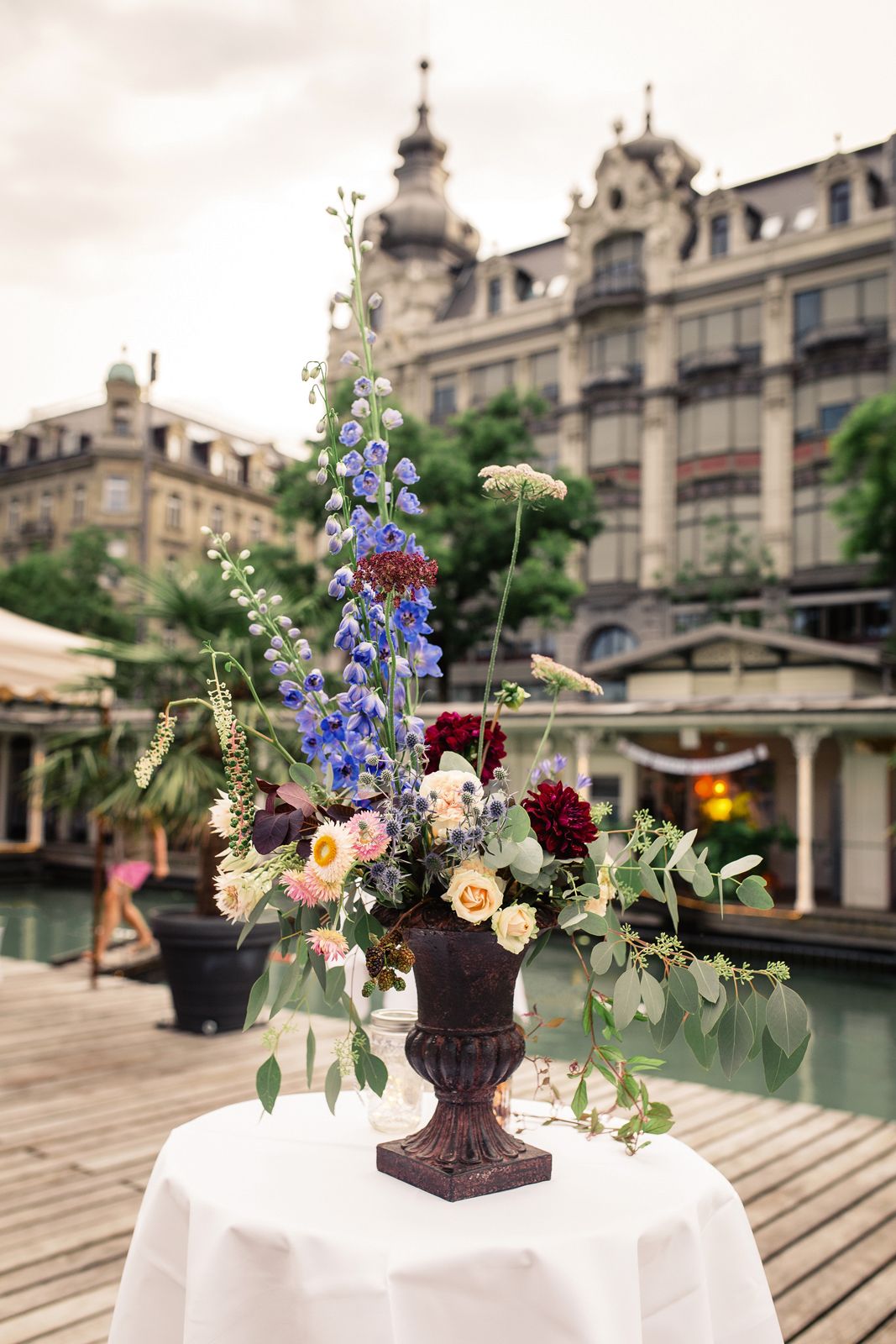 Elegant outdoor wedding floral arrangement in a tall vase at a historic Zurich venue.
