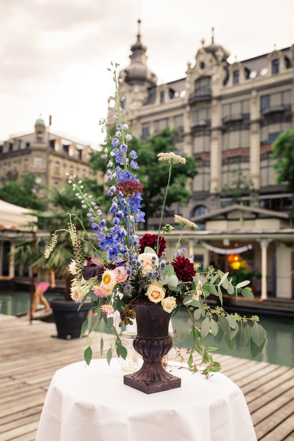 Elegant outdoor wedding floral arrangement in a tall vase at a historic Zurich venue.