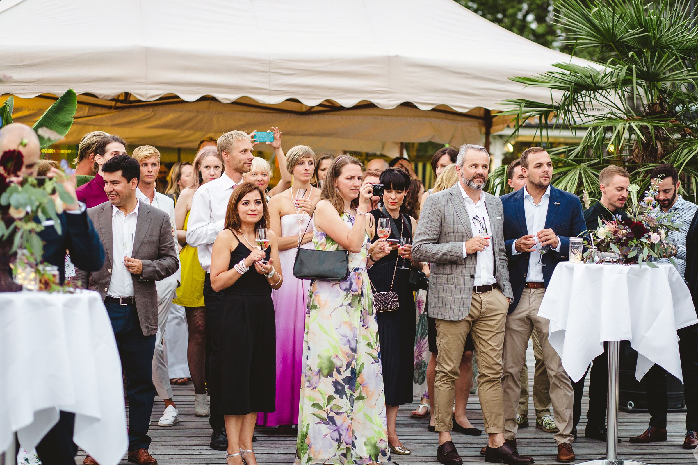 A group of wedding guests enjoying an outdoor reception, surrounded by elegant decorations and a festive atmosphere.