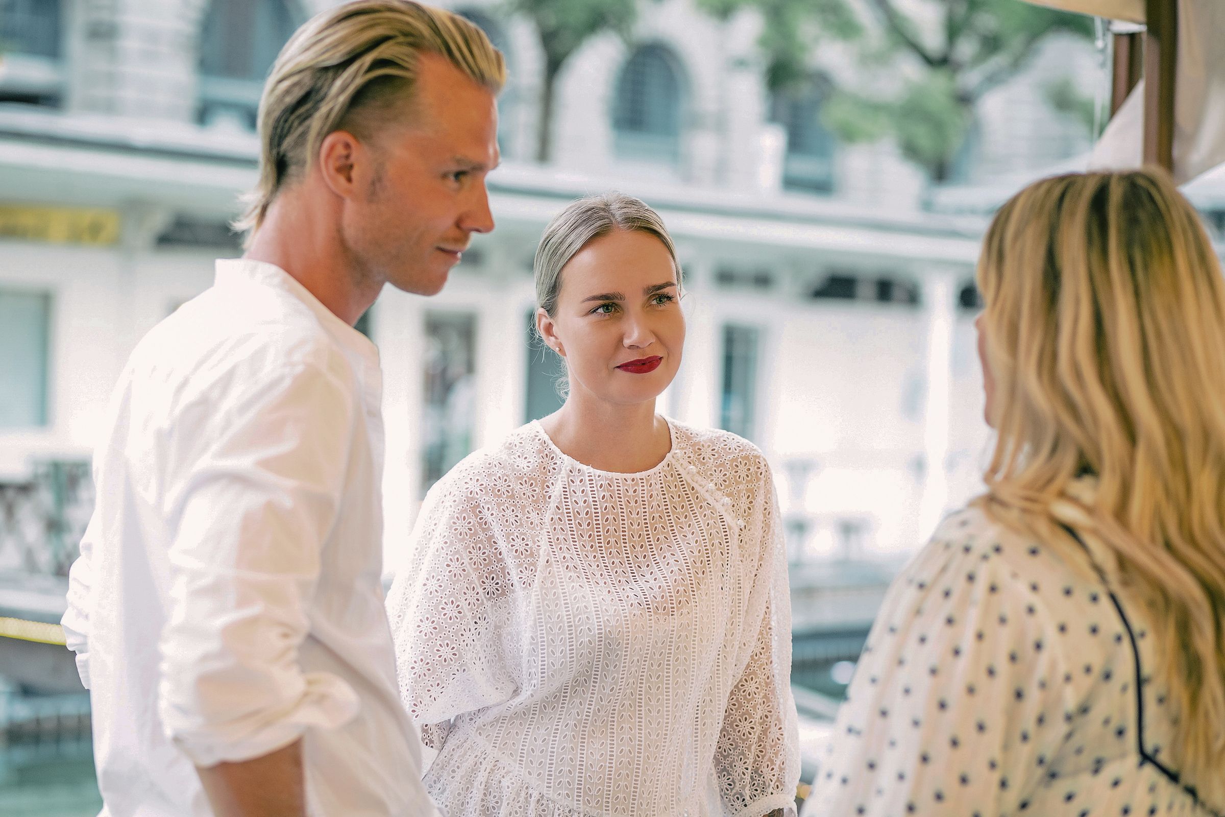 Group of friends wearing white, chatting outdoors.