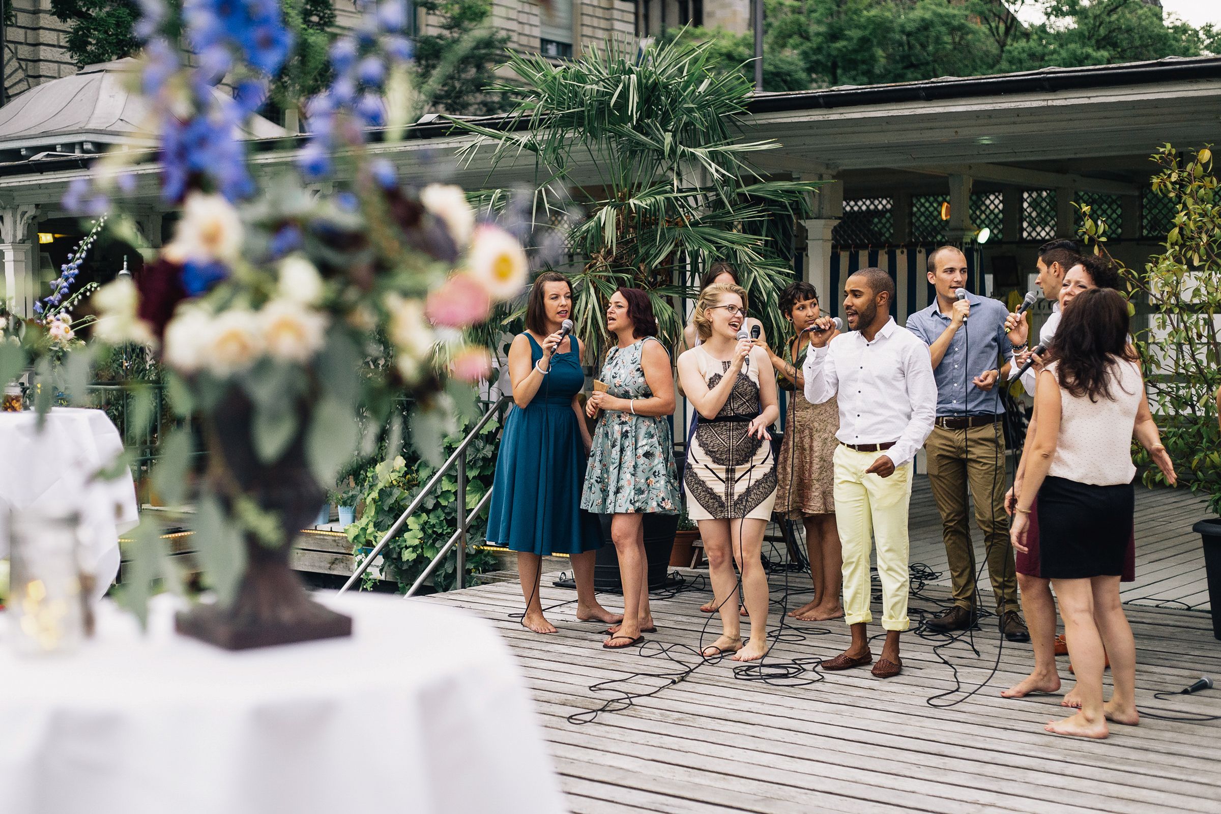 Cheerful multi cultured friends singing with microphone, standing outdoors.