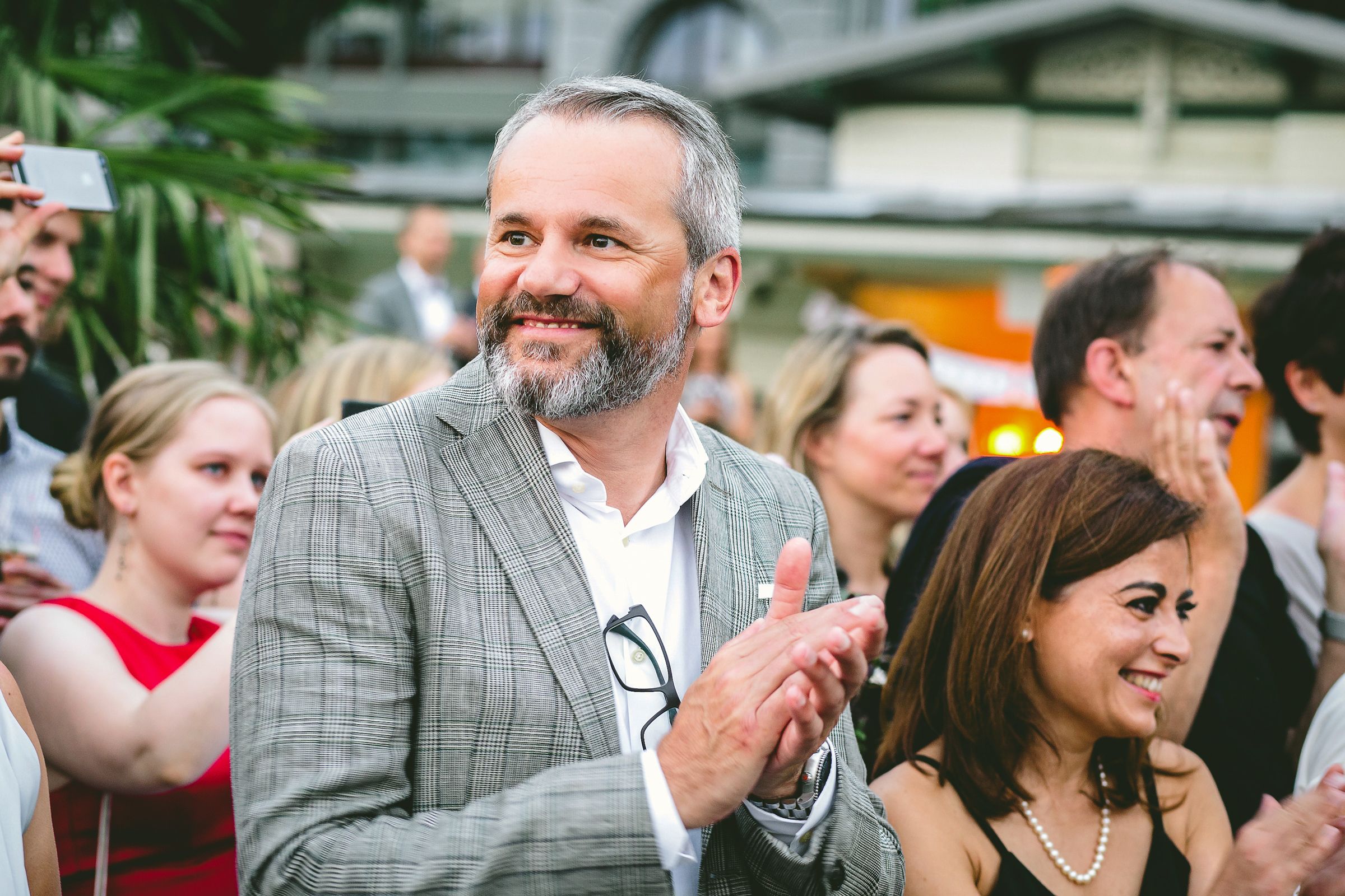 Portrait of smiling man standing with friends at a party, applauding