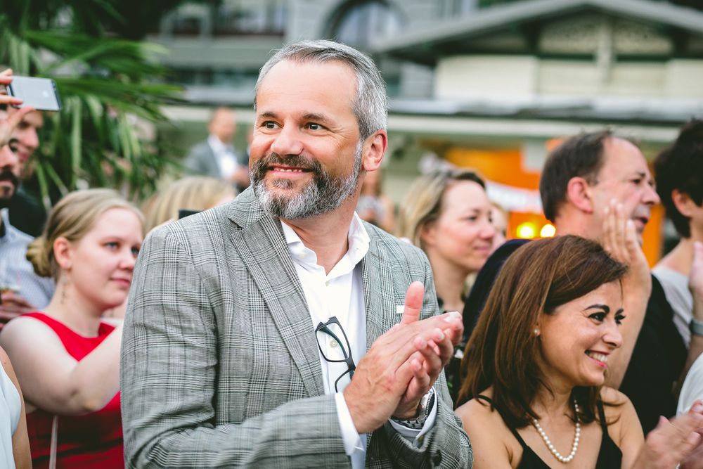 Portrait of smiling man standing with friends at a party, applauding