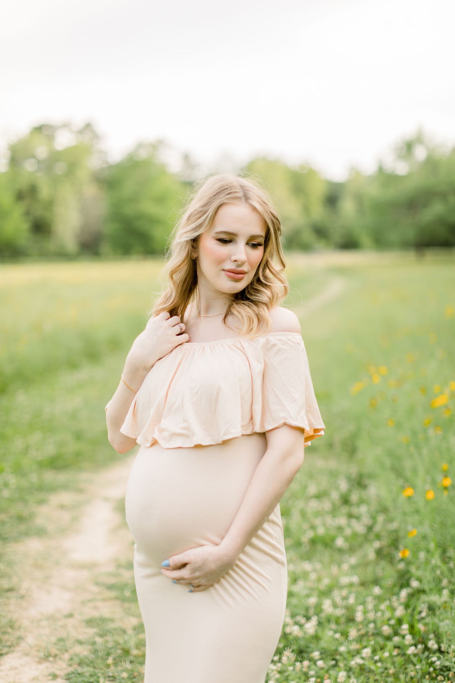 An ethereal maternity portrait in a blush gown surrounded by spring wildflowers.