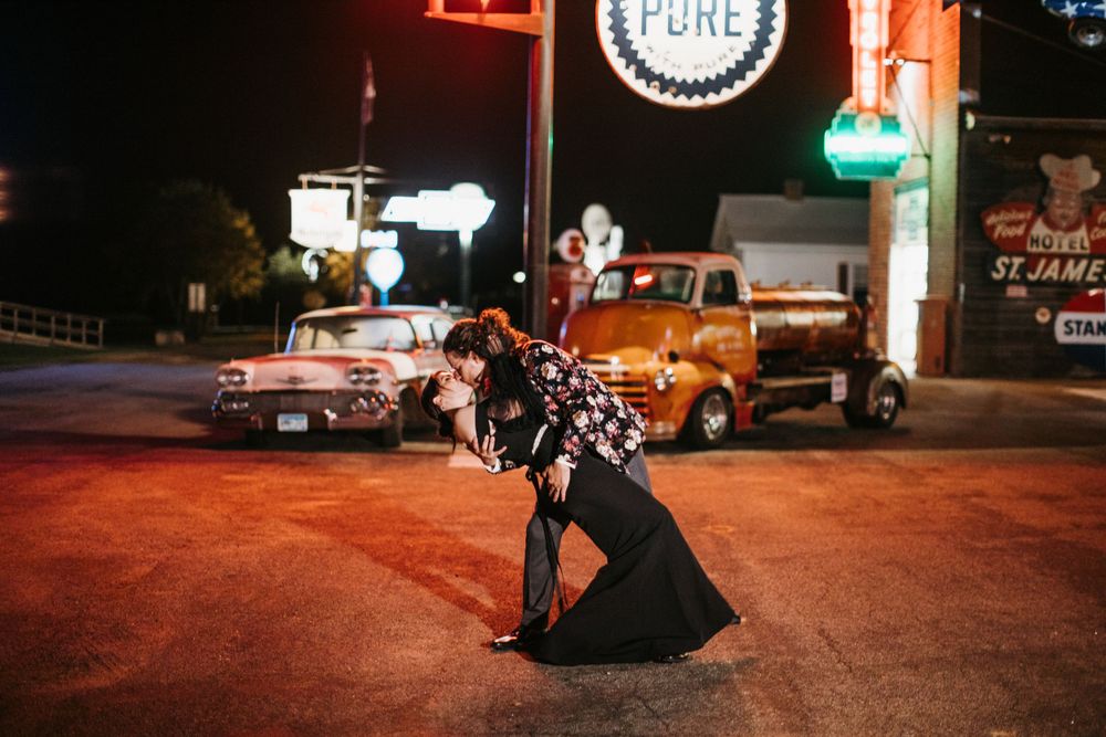 Couple sharing a dramatic dip kiss on a colorful neon-lit street at night.