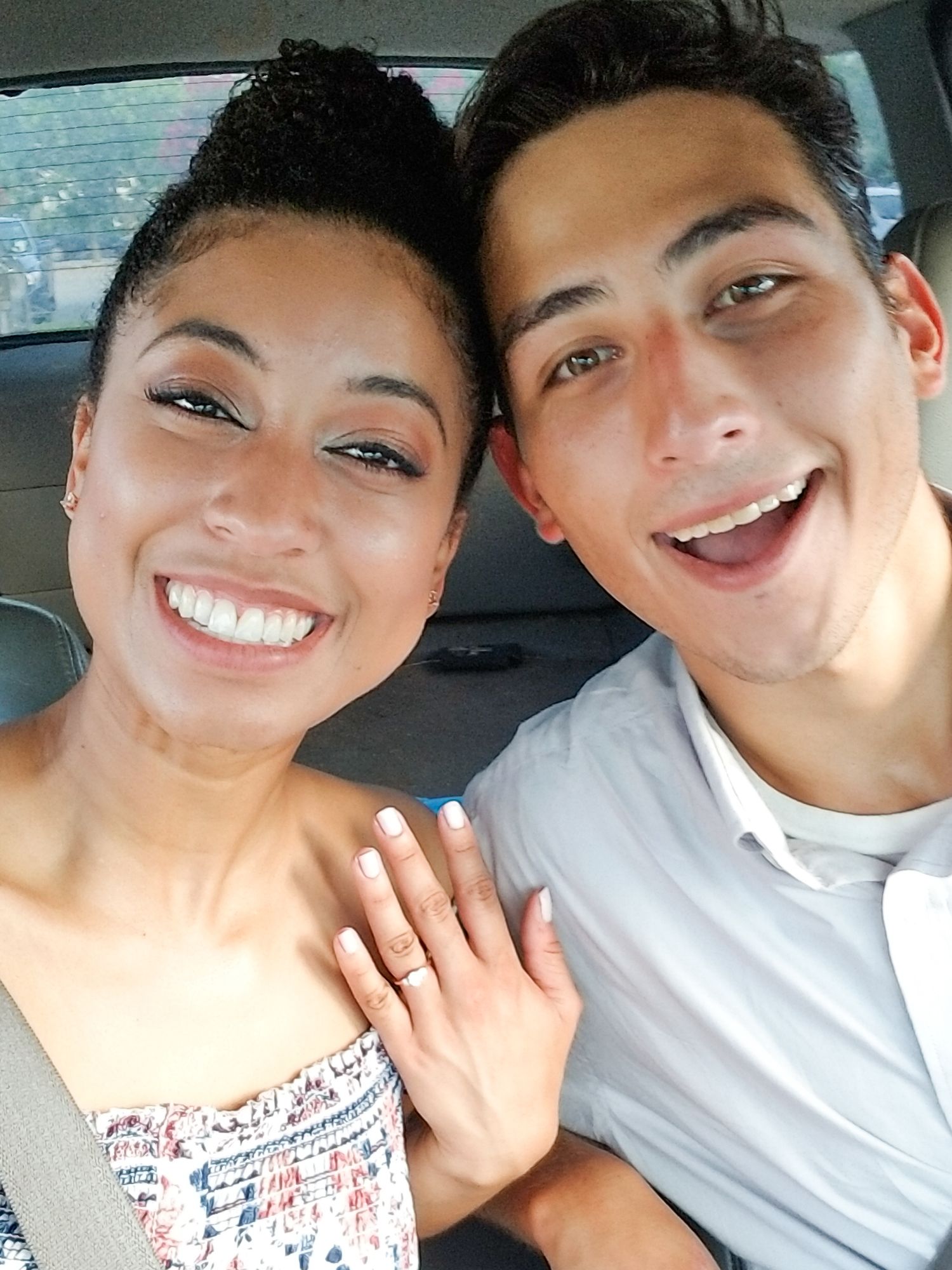 A car selfie showing a newly engaged couple displaying an engagement ring.