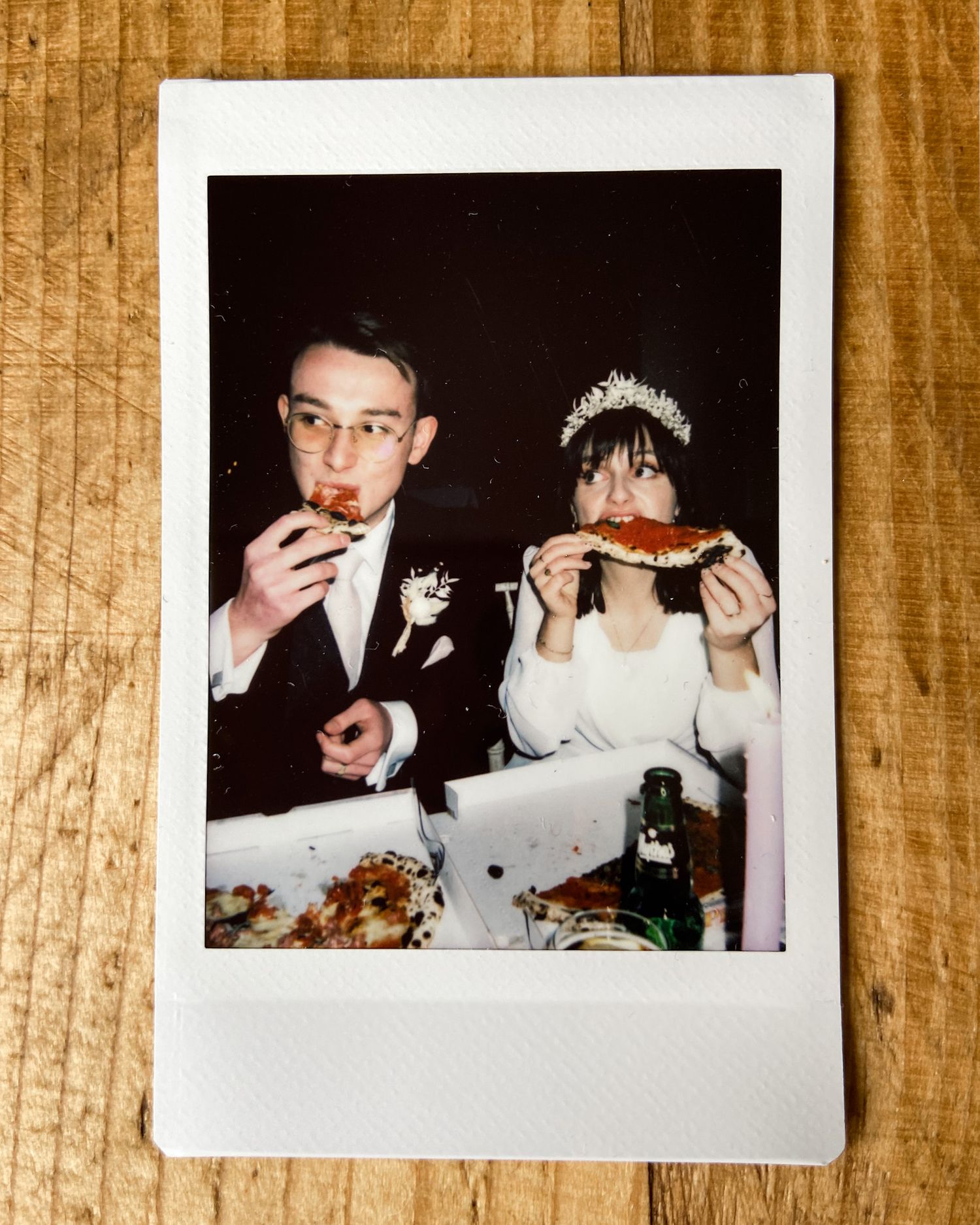 Vintage polaroid captures newlyweds enjoying their wedding meal with playful expressions.