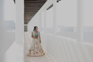 A couple in traditional attire poses against geometric white walls and wooden beams.