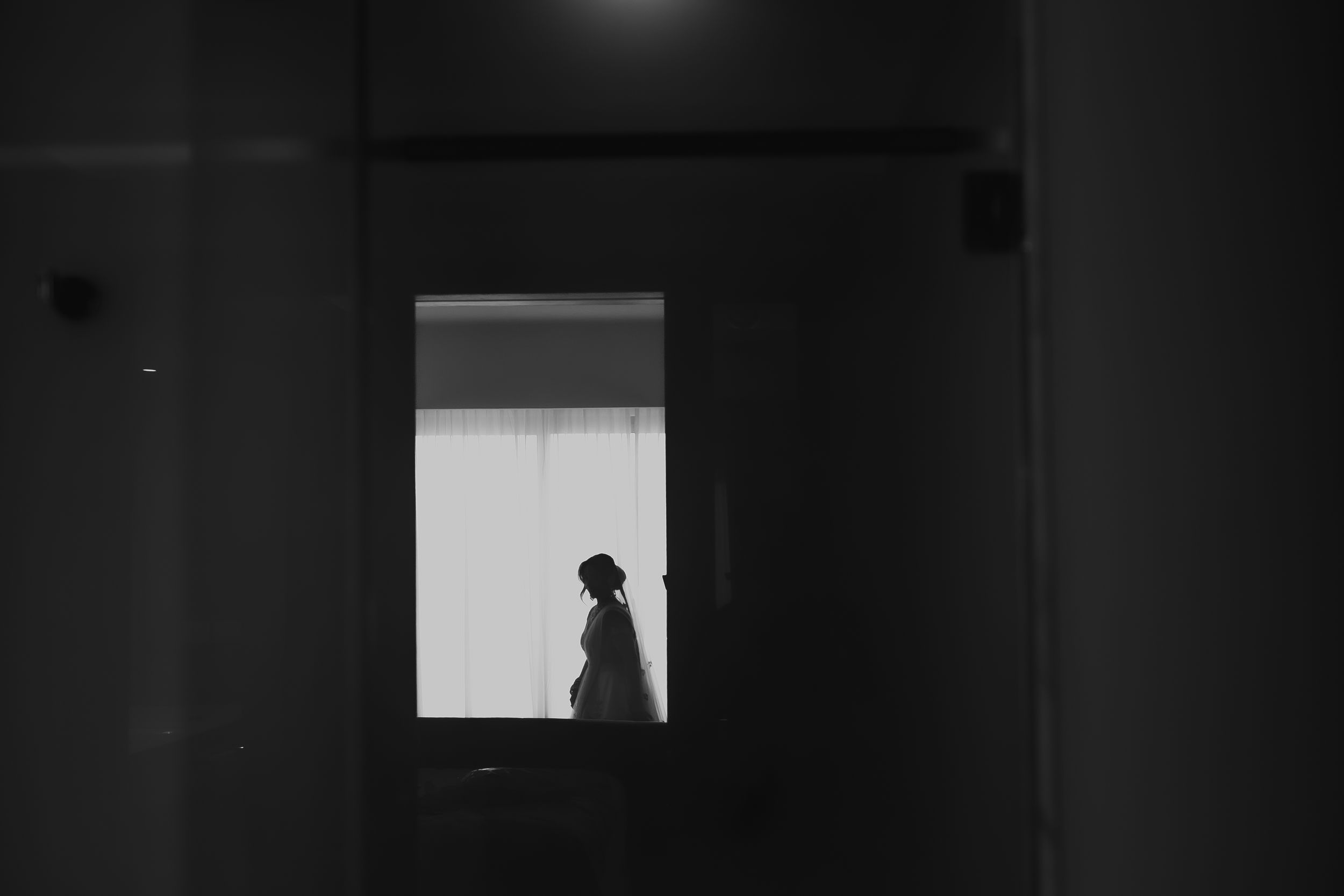 Dramatic silhouette of a bride framed in a doorway with natural backlight.