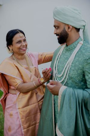 Candid moment showing traditional Indian wedding attire and joyful interaction.