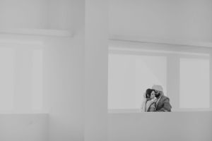 Two people embracing in a minimalist architectural setting captured in black and white.