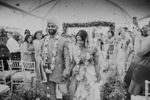 Wedding celebration with guests showering flower petals on couple during ceremony.
