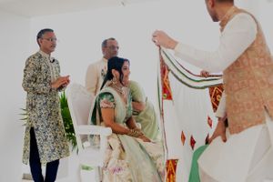 Family members participate in a traditional wedding ceremony ritual with decorative fabric.