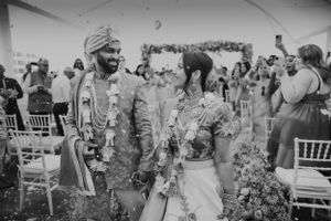 Newlyweds sharing happy moment during recessional at outdoor wedding ceremony.