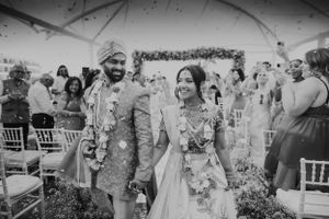 Couple walking down aisle after ceremony while guests celebrate with flower petals.