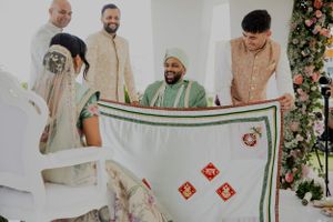 Wedding guests gather around a ceremonial cloth with red embroidered decorations.