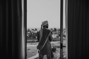Silhouette of person standing by window with palm trees visible outside.