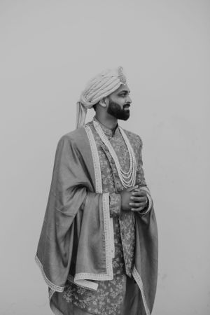 Black and white portrait of man in traditional Indian wedding attire.