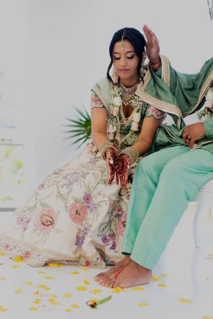 Bride in traditional Indian wedding attire showing intricate henna designs on her hands.