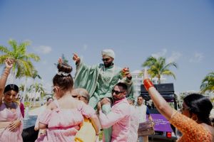 Joyful outdoor wedding celebration with guests dancing under palm trees.