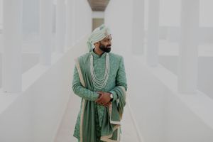 A couple in traditional attire walking through a modern white architectural hallway.
