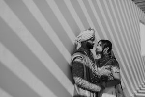A couple shares tender moments in a striking white geometric hallway.