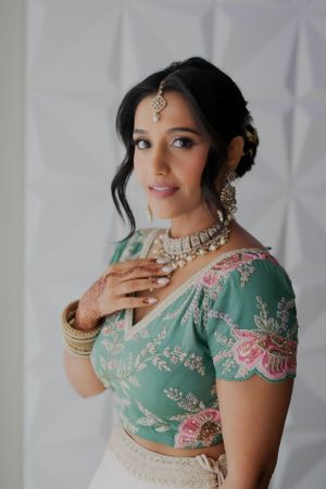 Traditional Indian bridal attire featuring a mint green embroidered blouse with ornate jewelry and henna designs.