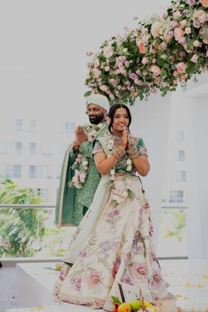 Couple poses under a beautiful pink floral arch during their wedding ceremony.