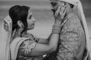 An intimate black and white portrait of a couple in traditional South Asian wedding attire.
