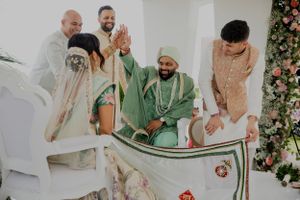 Wedding ceremony participants hold a traditional decorated white cloth during festivities.
