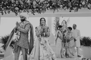 Couple celebrating their joyous wedding ceremony under floral decor and traditional Indian attire.