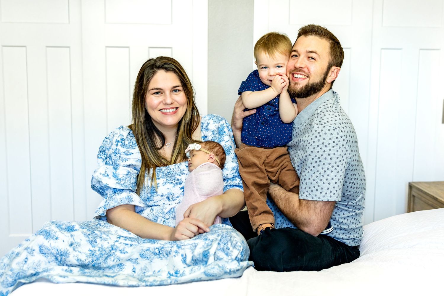 Parents hold their toddler boy and new baby girl and smile during newborn photos in Colorado Springs.