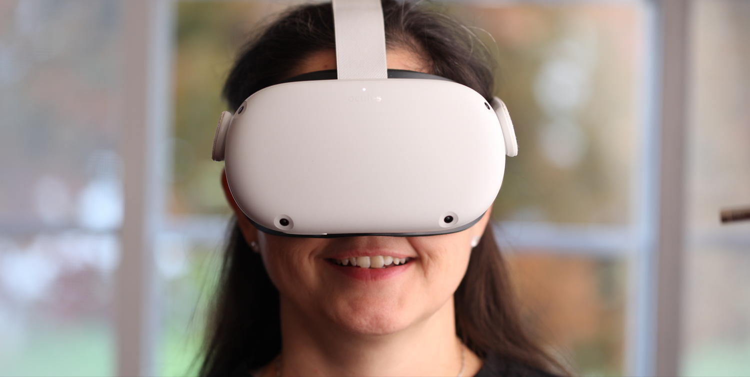Woman wearing white Meta Quest VR headset smiling while experiencing virtual reality.
