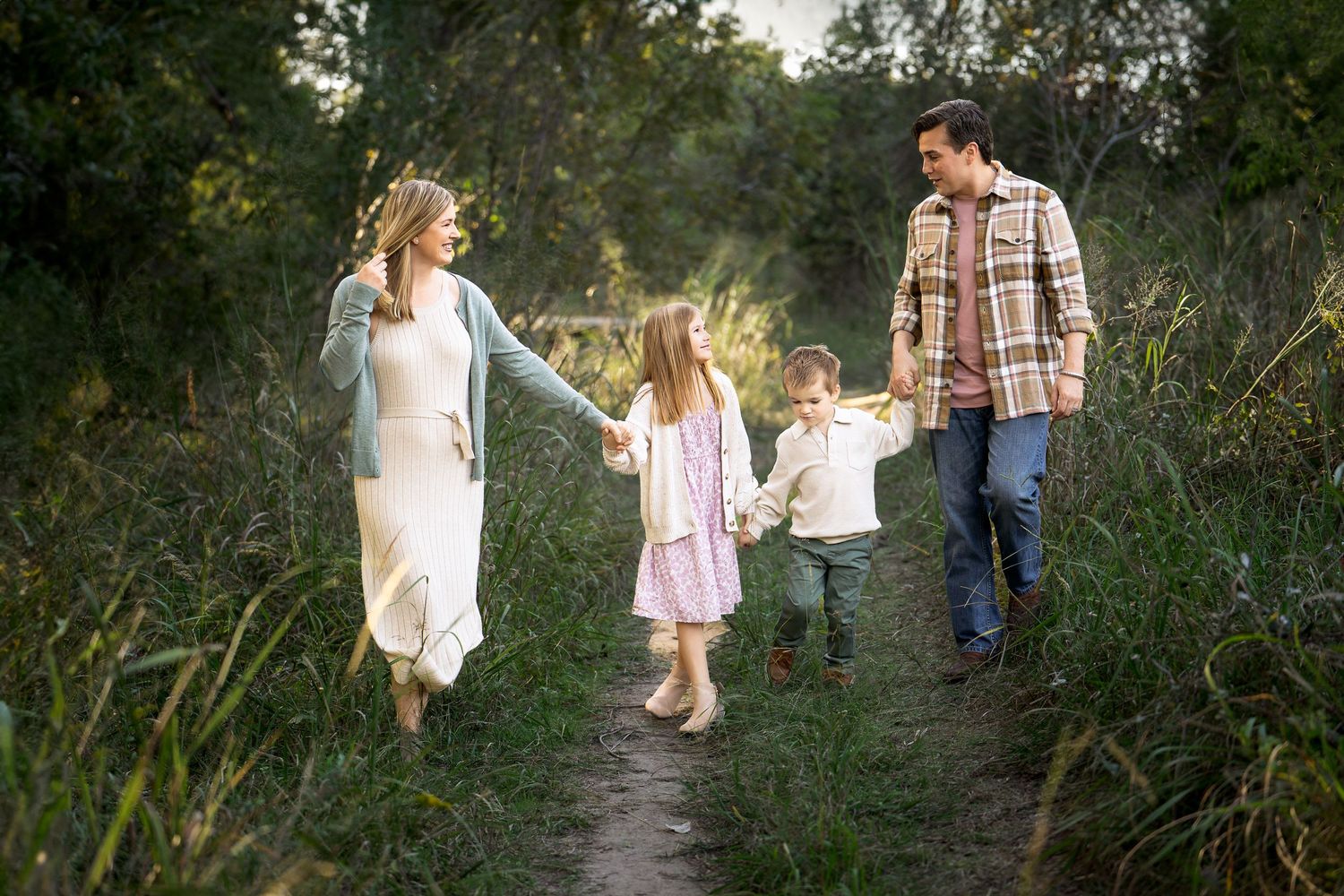 family photo of mom, dad and children holding hands while walking down a pathway smiling at each other in Boerne, TX