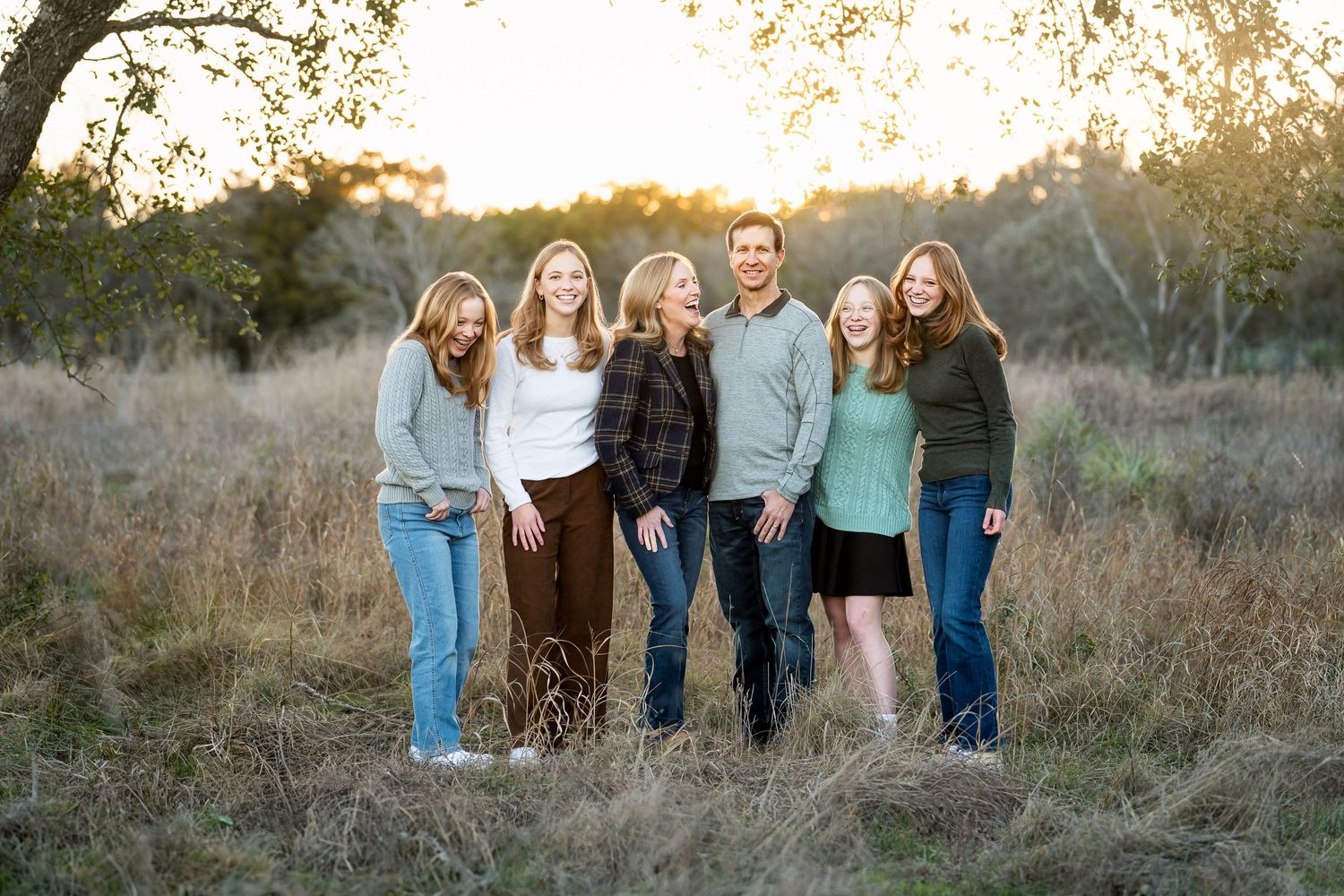 mom, dad and four teen daughters stand in field at golden hour in Phil Hardberger Park