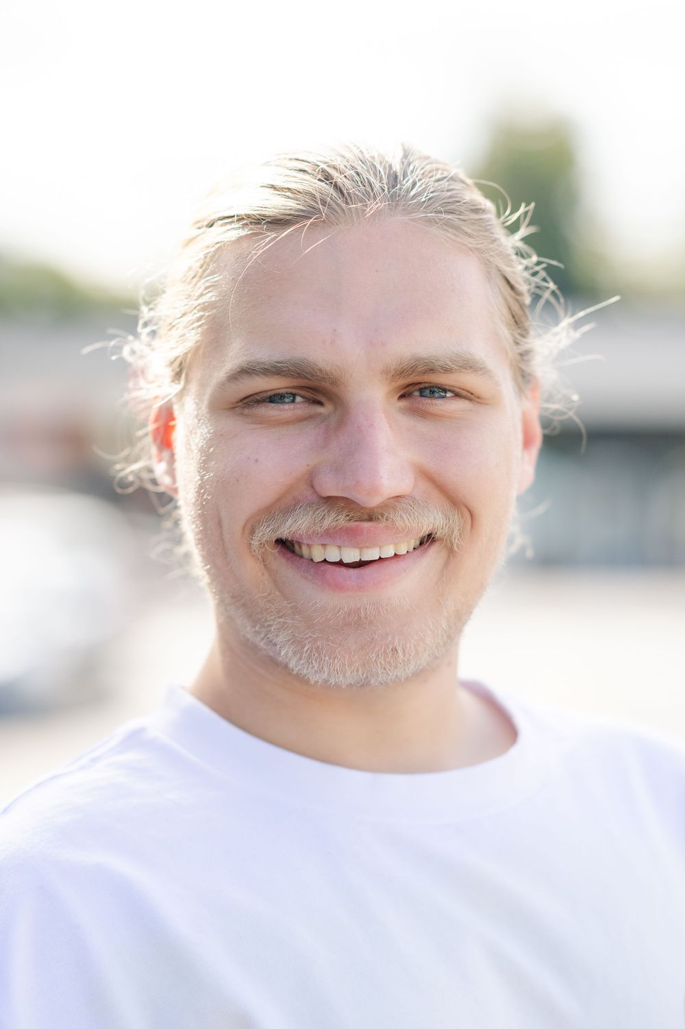 A young man smiles at the camera while having his picture taken by a professional portrait photographer in Venice Beach,